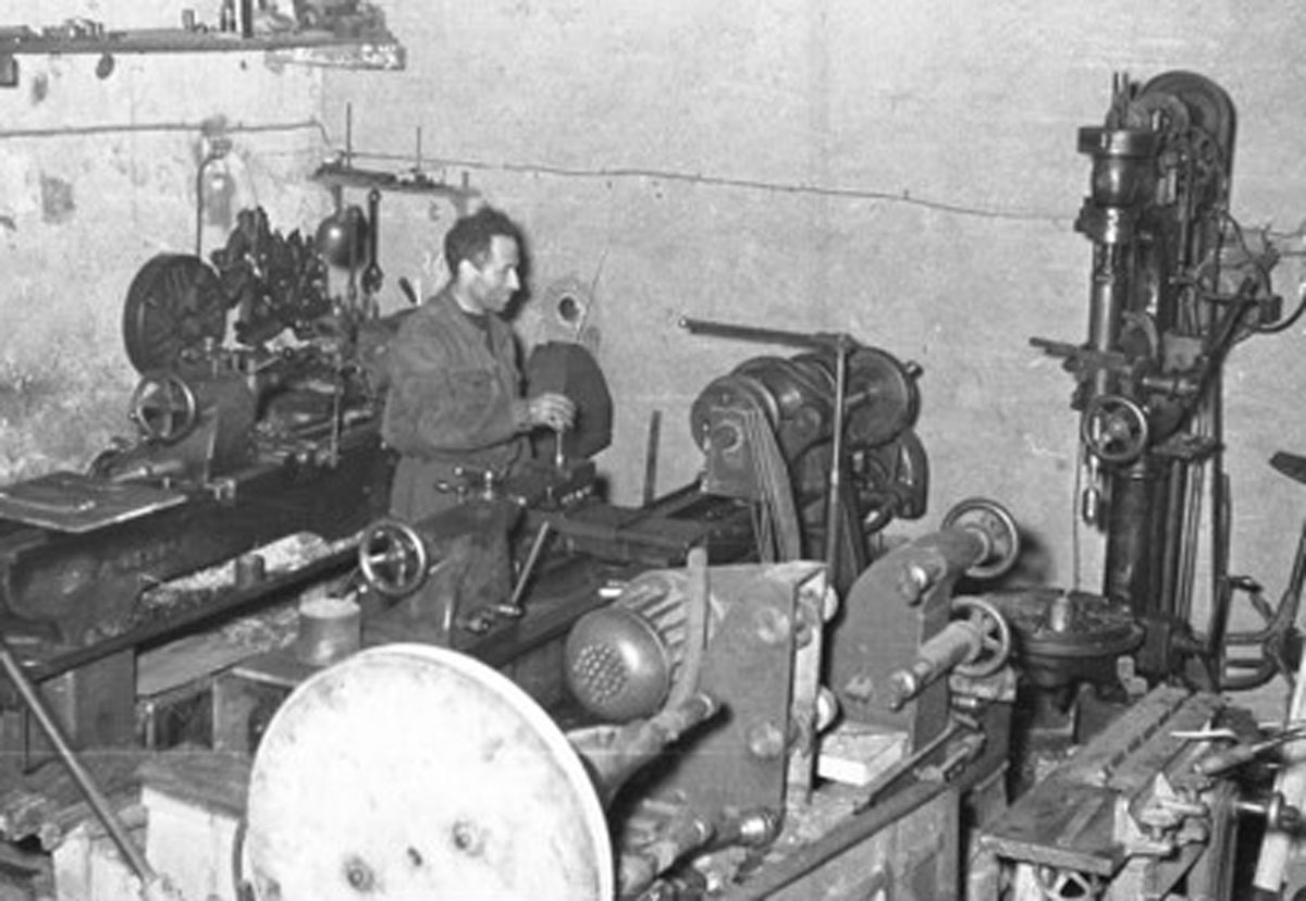 Officina meccanica negli anni '50 con operatore al tornio.