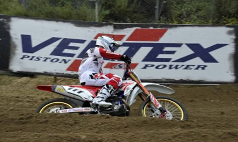 Pilota di motocross in curva su pista sterrata durante una gara