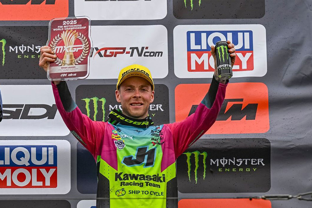 Romain Febvre sul podio del MXGP Germania 2025 con targa rossa di leader del mondiale motocross FIM e lattina Monster Energy in mano